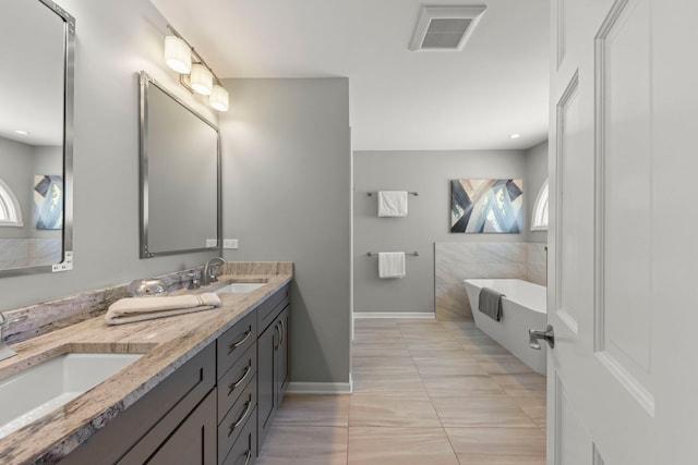 full bath featuring a bath, double vanity, visible vents, and a sink