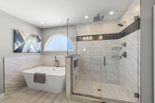 bathroom with a stall shower, tile walls, and a freestanding bath