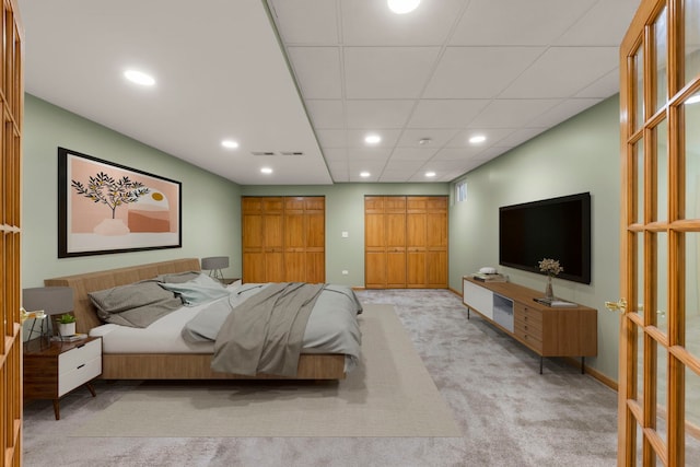 bedroom featuring baseboards, light colored carpet, a paneled ceiling, multiple closets, and recessed lighting