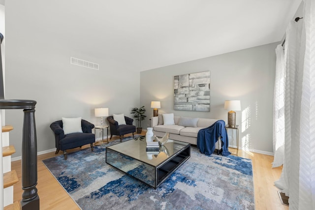 living area with visible vents, baseboards, and wood finished floors