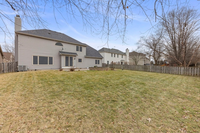 back of property with central air condition unit, a fenced backyard, and a yard