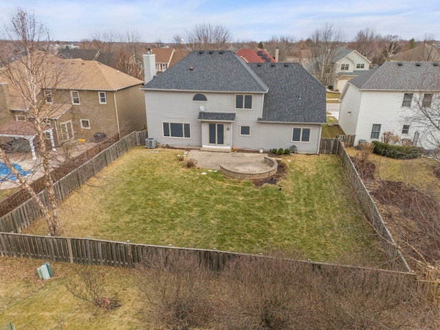 rear view of property with a fenced backyard, a lawn, and roof with shingles