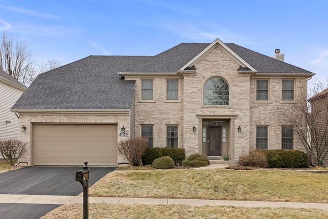 view of front of home featuring a shingled roof, a chimney, aphalt driveway, and brick siding