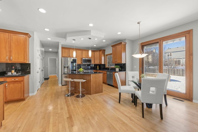 kitchen featuring visible vents, appliances with stainless steel finishes, a center island, tasteful backsplash, and dark countertops