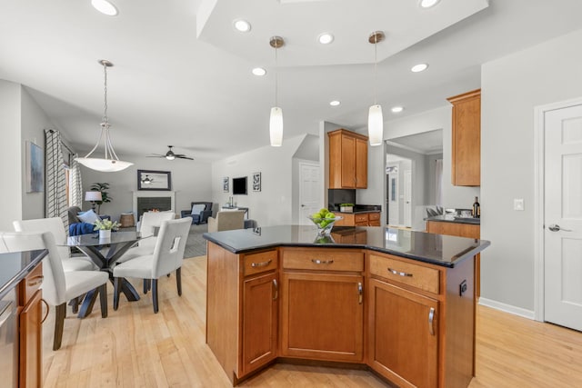 kitchen featuring light wood-style flooring, recessed lighting, a fireplace, a kitchen island, and open floor plan