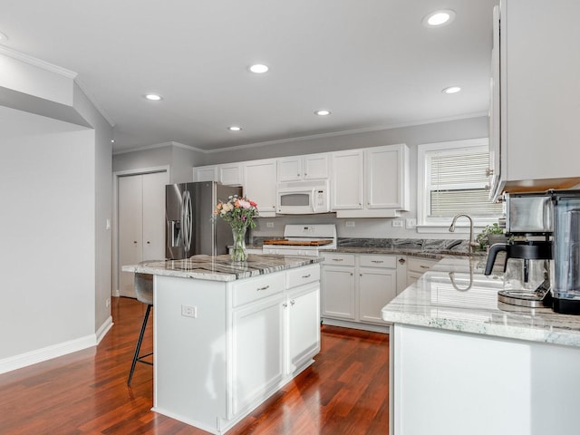 kitchen featuring white cabinetry, a center island, light stone counters, and white appliances