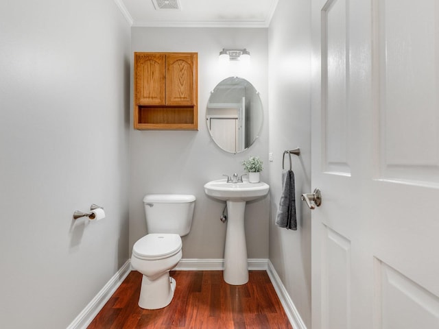 bathroom featuring hardwood / wood-style flooring, ornamental molding, sink, and toilet