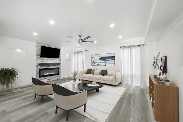 living room with ceiling fan, light hardwood / wood-style floors, and a tile fireplace