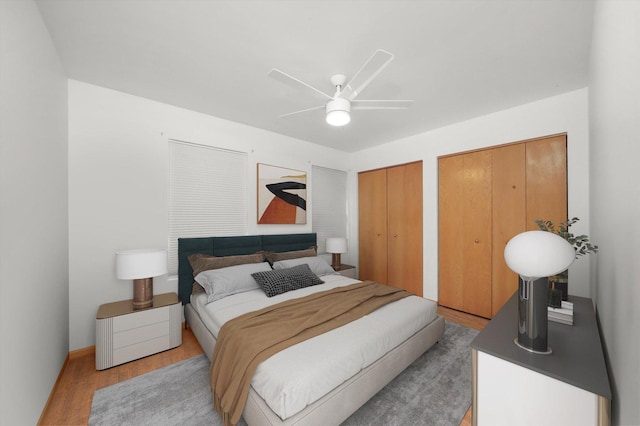 bedroom featuring two closets, ceiling fan, and light wood-type flooring