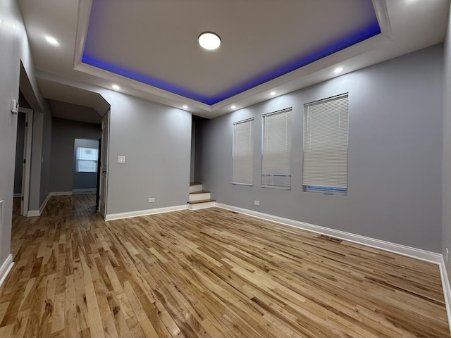 unfurnished room featuring a tray ceiling and light hardwood / wood-style flooring