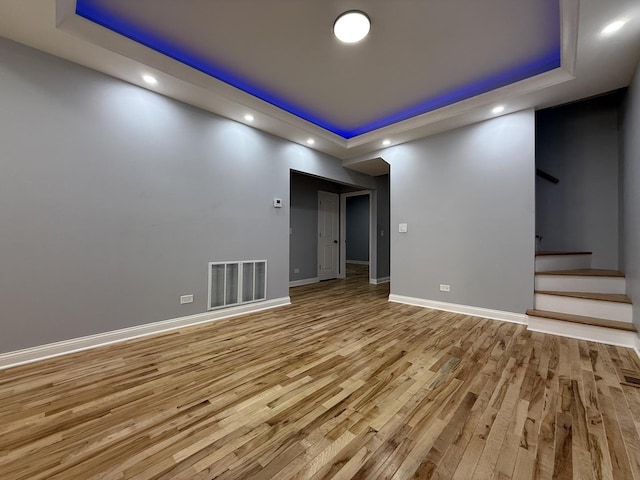 unfurnished room featuring a tray ceiling and light wood-type flooring