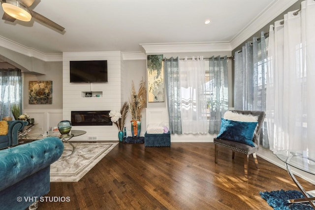 living room with dark hardwood / wood-style floors, crown molding, plenty of natural light, and a large fireplace