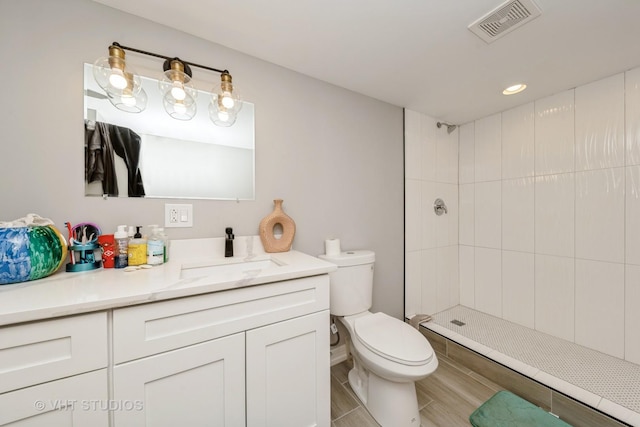 bathroom with vanity, a tile shower, and toilet