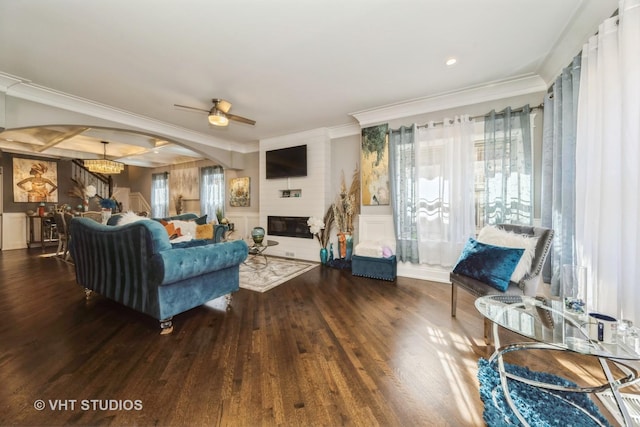 living room featuring coffered ceiling, ornamental molding, hardwood / wood-style flooring, a fireplace, and ceiling fan with notable chandelier