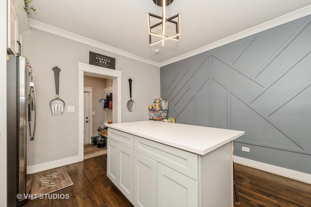 kitchen featuring white cabinetry, stainless steel fridge, hanging light fixtures, crown molding, and light stone countertops