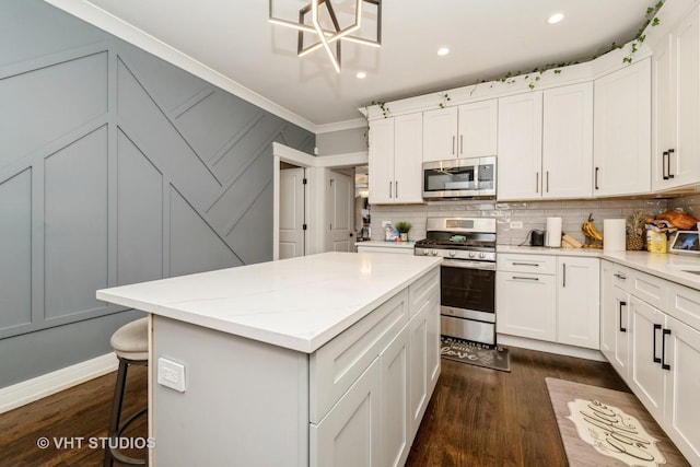 kitchen with a kitchen island, appliances with stainless steel finishes, a breakfast bar area, and white cabinets