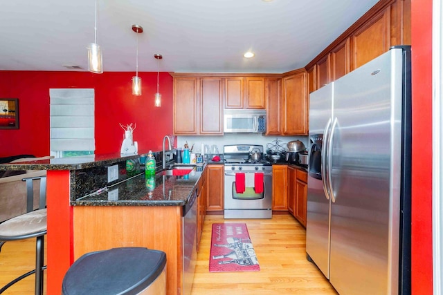 kitchen featuring pendant lighting, sink, dark stone countertops, a breakfast bar area, and stainless steel appliances