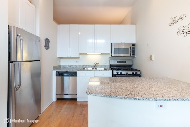 kitchen with sink, white cabinetry, stainless steel appliances, light hardwood / wood-style floors, and light stone countertops