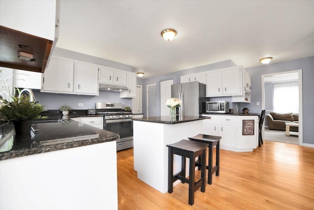 kitchen with stainless steel appliances, a kitchen island, white cabinets, and light hardwood / wood-style floors