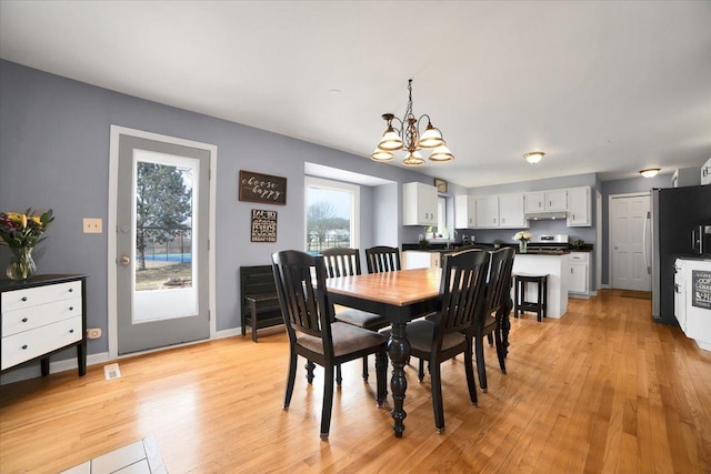 dining space with light hardwood / wood-style floors and a notable chandelier