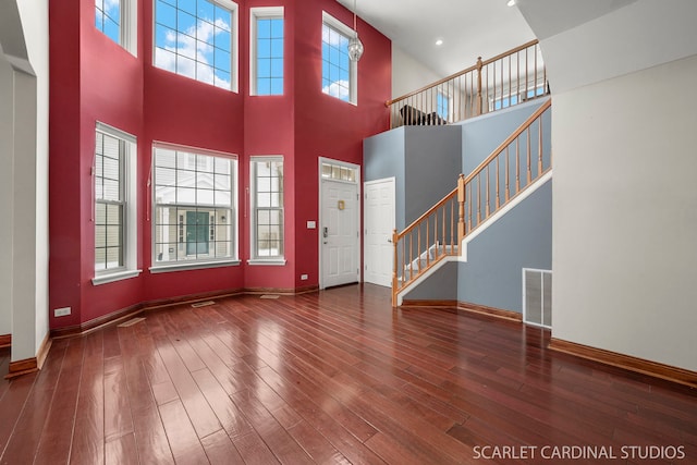 unfurnished living room featuring plenty of natural light and dark hardwood / wood-style flooring