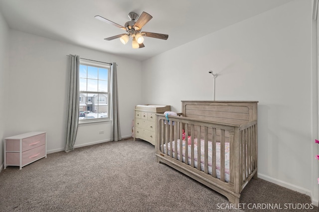 carpeted bedroom featuring a nursery area and ceiling fan