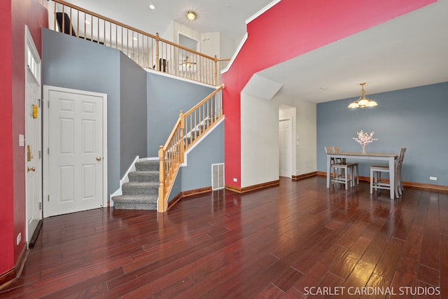 interior space with dark hardwood / wood-style floors, a chandelier, and a high ceiling