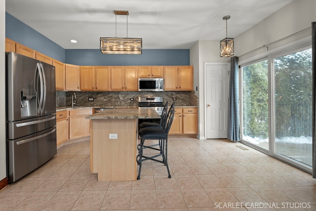 kitchen featuring a kitchen island, appliances with stainless steel finishes, a breakfast bar, decorative light fixtures, and light stone counters