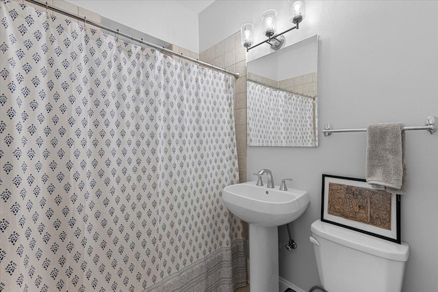 bathroom featuring a shower with curtain, toilet, and sink