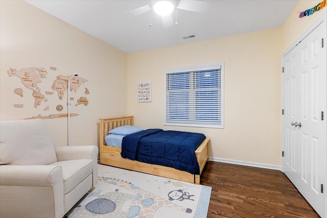 bedroom with dark wood-style flooring, a closet, visible vents, and baseboards