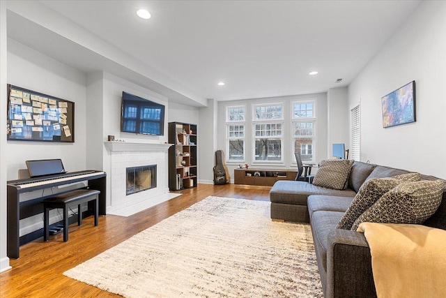 living area with a fireplace, baseboards, wood finished floors, and recessed lighting