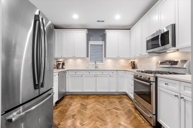 kitchen featuring stainless steel appliances, light countertops, and white cabinetry