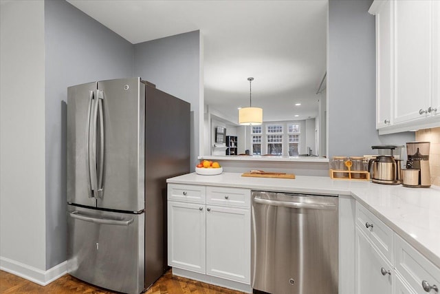 kitchen featuring appliances with stainless steel finishes, white cabinets, light stone counters, and pendant lighting