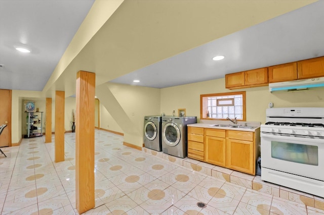 kitchen with sink, washing machine and clothes dryer, light tile patterned floors, and white gas stove