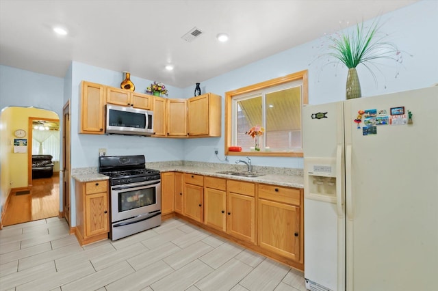 kitchen with appliances with stainless steel finishes, sink, and light stone counters