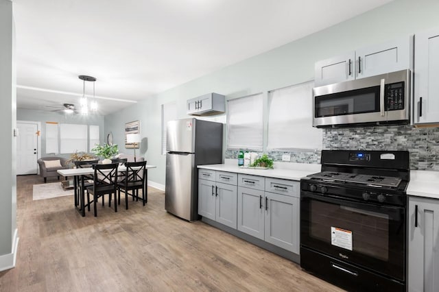 kitchen with stainless steel appliances, gray cabinets, decorative backsplash, and light hardwood / wood-style flooring