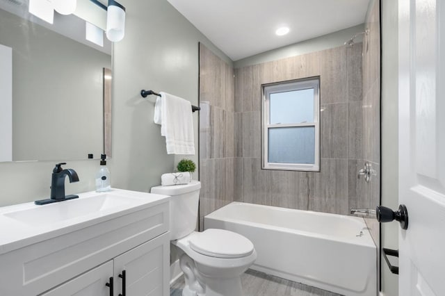 full bathroom featuring vanity, tiled shower / bath combo, and toilet