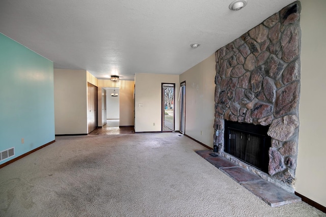 unfurnished living room featuring a stone fireplace, a textured ceiling, and carpet flooring