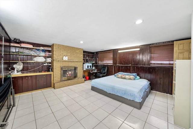 tiled bedroom featuring a brick fireplace and wood walls