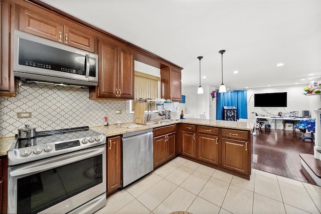 kitchen featuring light tile patterned flooring, appliances with stainless steel finishes, kitchen peninsula, pendant lighting, and decorative backsplash