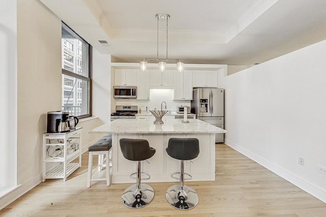 kitchen with white cabinetry, appliances with stainless steel finishes, a tray ceiling, and hanging light fixtures