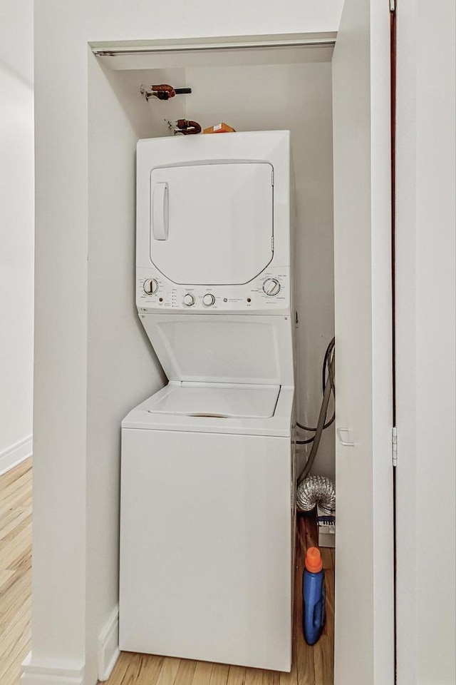 clothes washing area featuring stacked washer / dryer and light wood-type flooring