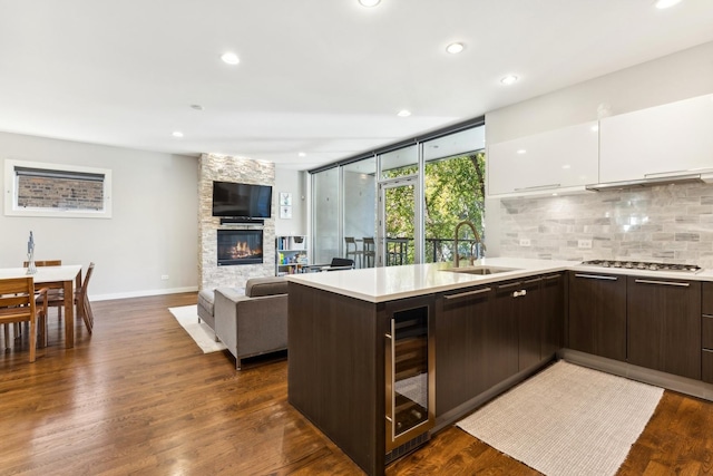 kitchen featuring sink, dark brown cabinets, a large fireplace, white cabinets, and beverage cooler