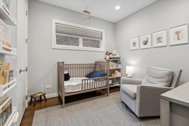 bedroom featuring hardwood / wood-style flooring and a nursery area