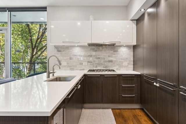 kitchen featuring sink, tasteful backsplash, dark hardwood / wood-style flooring, stainless steel gas stovetop, and white cabinets