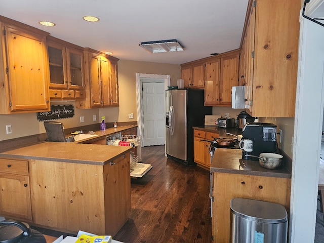 kitchen featuring dark hardwood / wood-style flooring, stainless steel fridge, and kitchen peninsula