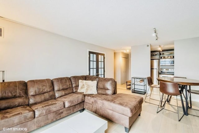 living room featuring french doors, track lighting, and light wood-type flooring