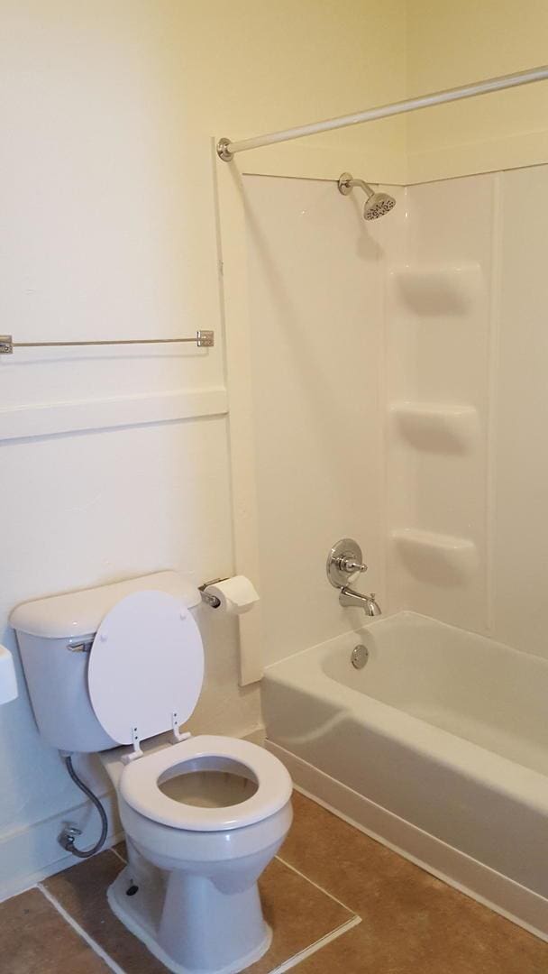 bathroom featuring washtub / shower combination, toilet, and tile patterned flooring