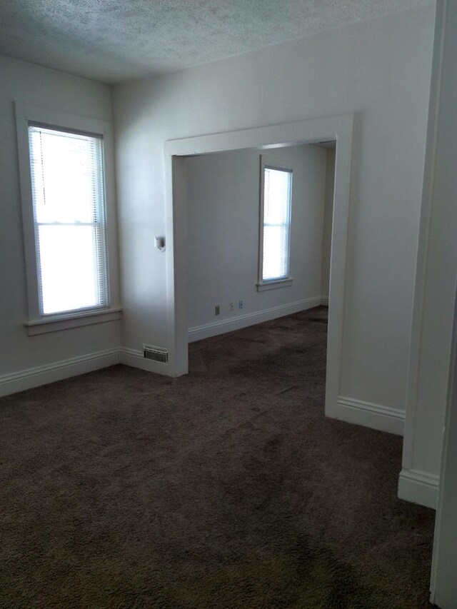 carpeted empty room featuring a textured ceiling