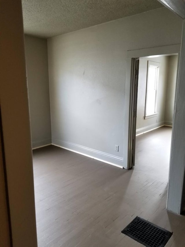 unfurnished room with wood-type flooring and a textured ceiling